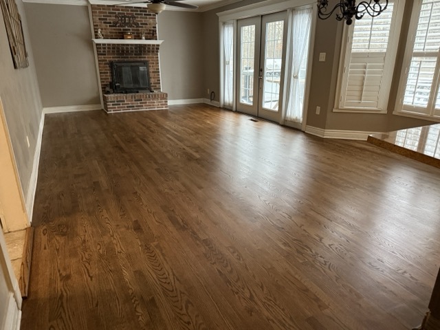 Refinished hardwood floors surrounding a brick fireplace in a Baltimore, MD home.